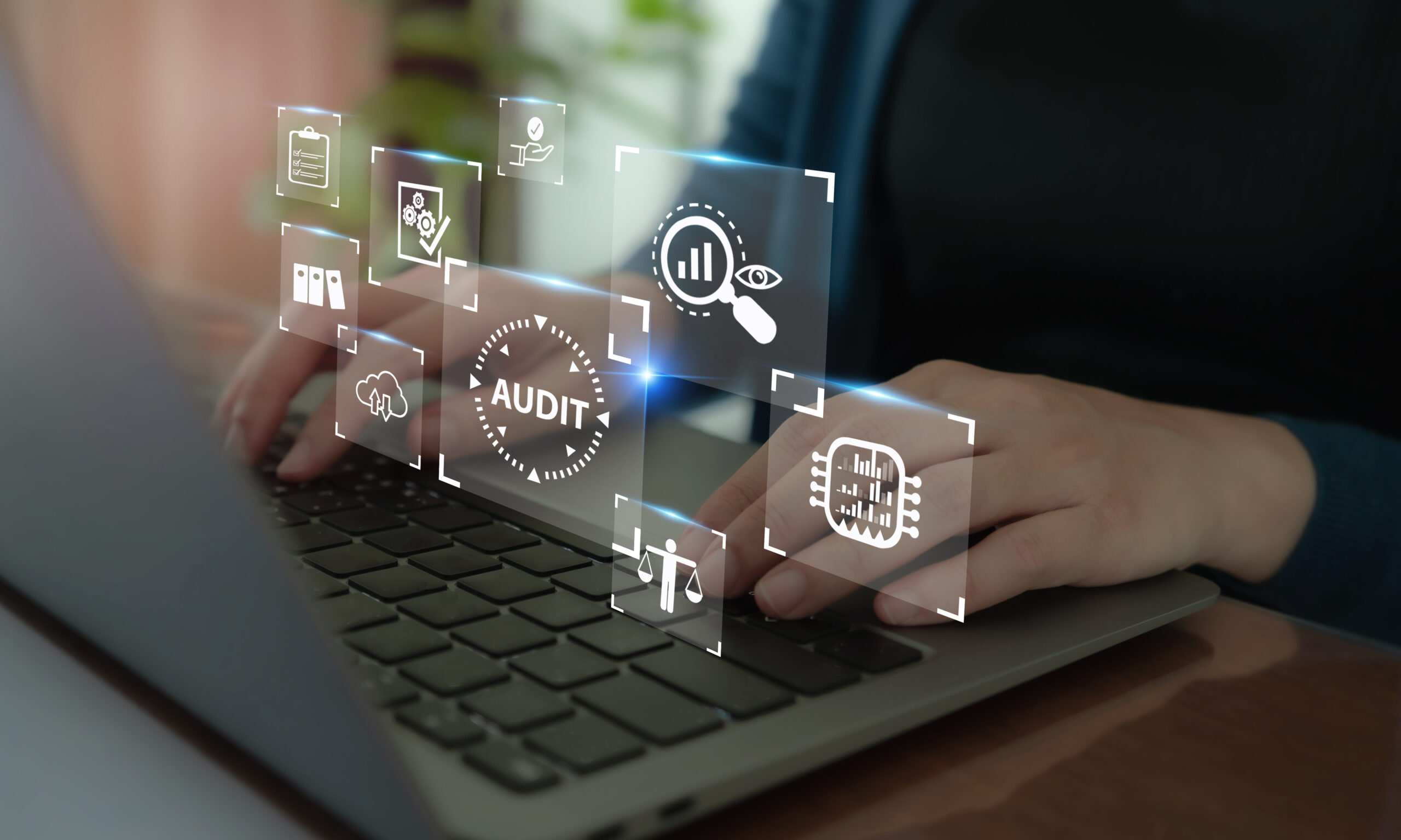 Mains tapant sur un clavier d’ordinateur portable avec des icônes numériques flottantes liées à l’audit, à l’analyse de données et à la validation de processus.